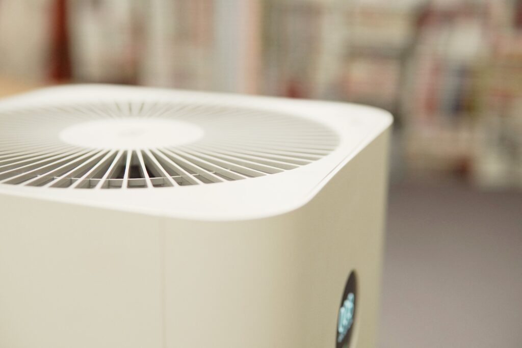 Close-up of the top part of a white air purifier with a circular vent design. A digital display is visible on the device's front.